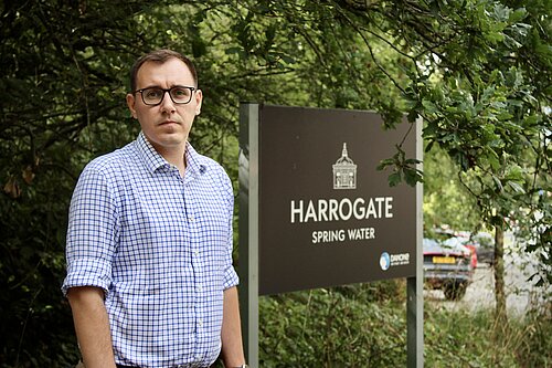 Tom Gordon MP standing next to Harrogate Spring Water sign