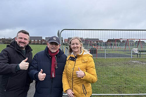 Councillors Martin Haswell, Steve Donkin and Julia Potts with their thumbs up standing in front of new children's play park equipment behind fencing at Blackie Park