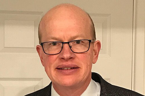 Paul de Kort is pictured wearing a suit, smiling and looking at the camera. 