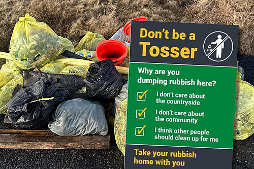 "Don't be a Tosser" poster in front of a picture of litter collected by local volunteers  