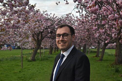 Tom stood in front of cherry blossoms