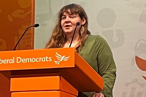 Katharine Macy standing behind a Lib Dem conference podium