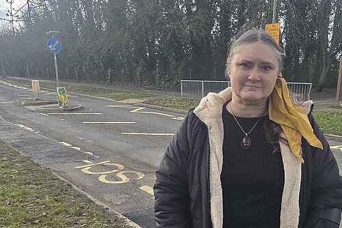 Councillor Andrew Bowes standing in front of a road full of pot holes