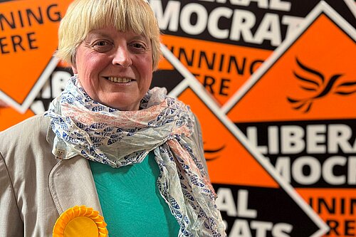 Liberal Democrat Candidate Jackie Pearcey in front of a sea of Lib Dem diamonds