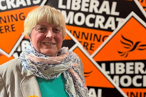 Liberal Democrat Candidate Jackie Pearcey in front of a sea of Lib Dem diamonds