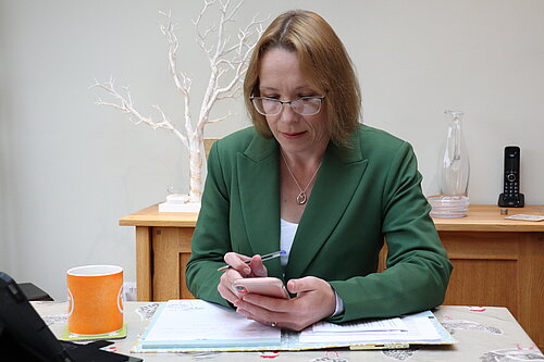 Helen at her desk with her mobile phone