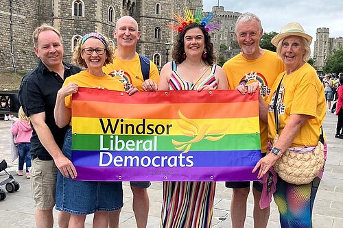 Mixed group of adults hold a pride banner outside Windsor Castle